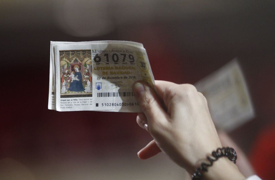 Una mujer agarra sus décimos antes de que comience el Sorteo Extraordinario de la Lotería de Navidad en el Teatro Real de Madrid.