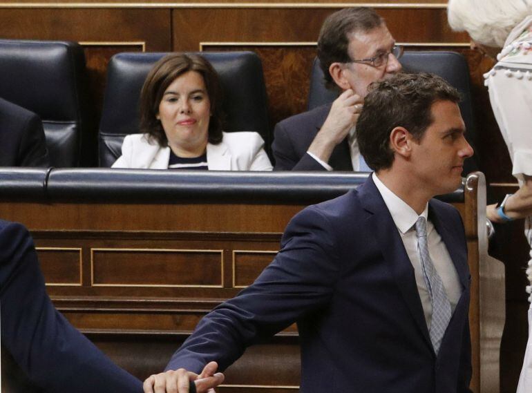 El presidente de Ciudadanos, Albert Rivera (d), pasa por delante de los escaños del presidente del Gobierno en funciones, Mariano Rajoy (detrás-d), y la vicepresidenta en funciones, Soraya Sáenz de Santamaría, cuando se dirige a votar en la sesión constit