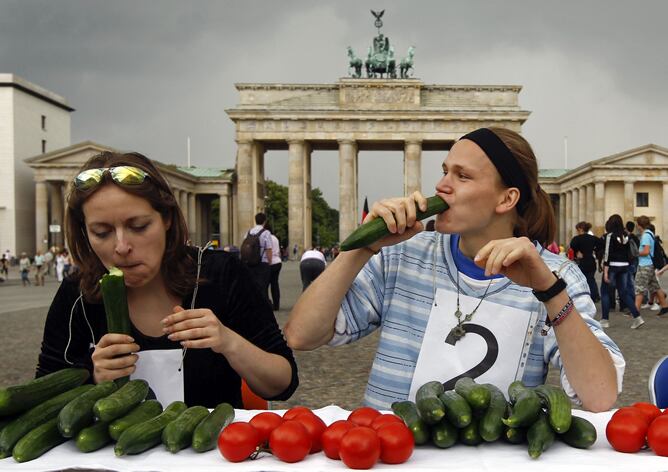 Dos jóvenes participan en un concurso de comer pepinos, frente a la Puerta de Brandenburgo, en Berlín (Alemania), este martes 14 de junio de 2011. La asociación de vegetarianos ha celebrado este concurso después de la crisis provocada en el sector hortofr