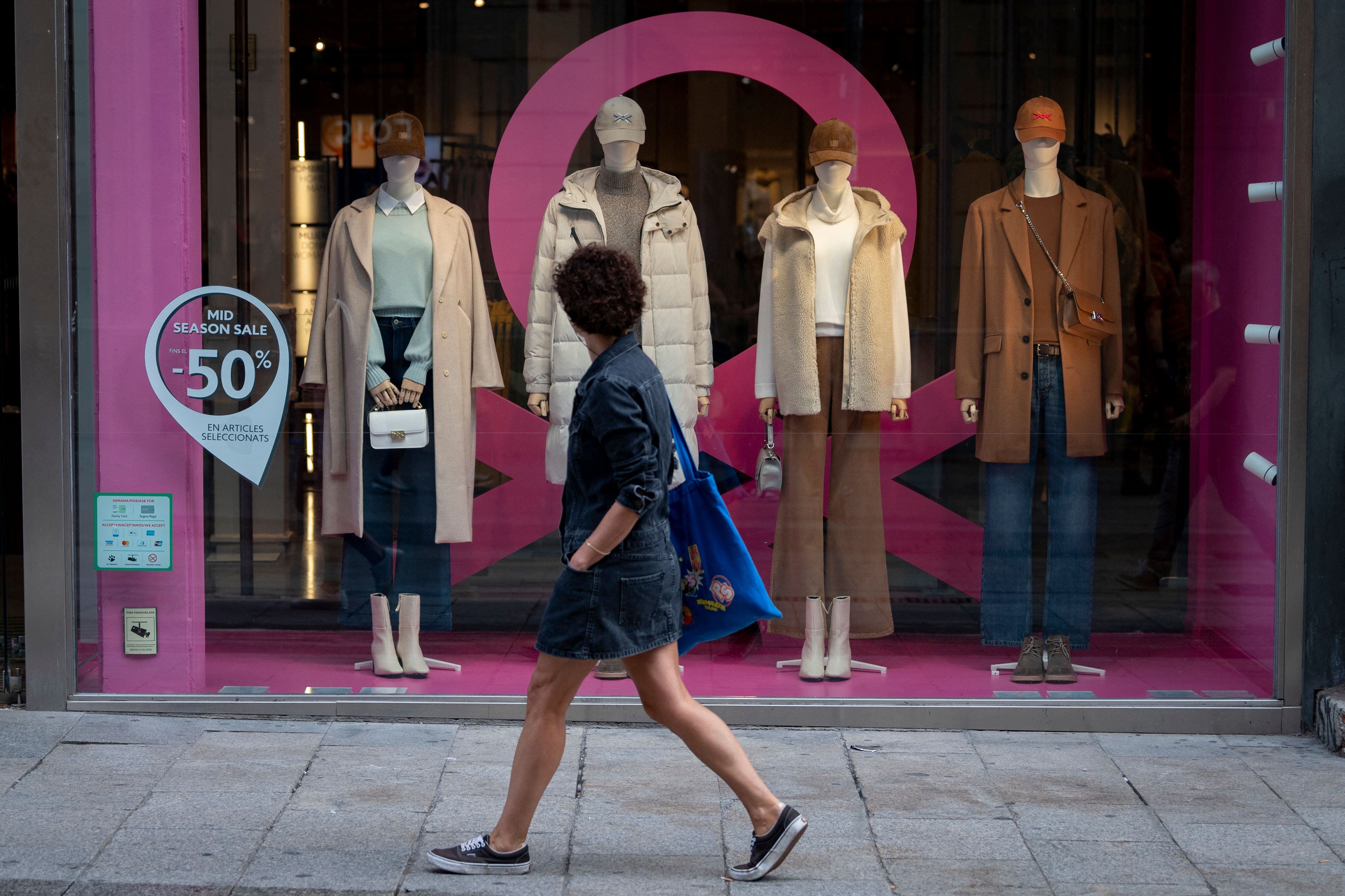 A woman walks past a shop window displaying autumn clothes in Barcelona on October 27, 2022. - After a summer marked by heat waves and devastating fires, Spain still faces exceptionally high temperatures at the end of October. (Photo by Josep LAGO / AFP) (Photo by JOSEP LAGO/AFP via Getty Images)