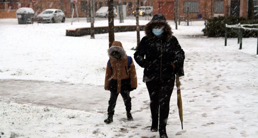 Una mujer y un niño caminan por una calle nevada  en Ciudad Real