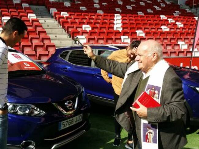 El padre Fueyo bendice el coche de Bernardo.