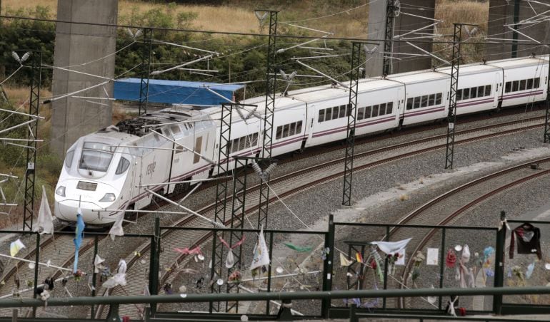 Un tren alvia similar al accidentado en Angrois, pasa esta tarde por la curva donde todavía permanecen objetos colocados en memoria de las 80 víctimas mortales