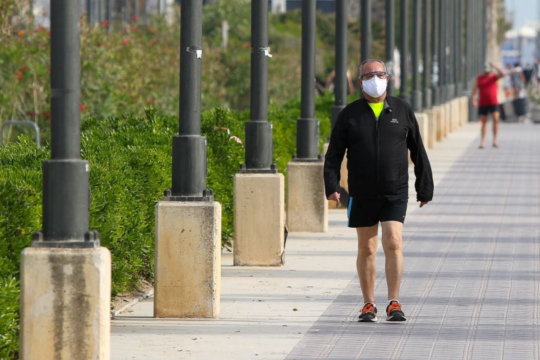 Archivo - Un hombre con mascarilla pasea por la playa de la Malvarrosa