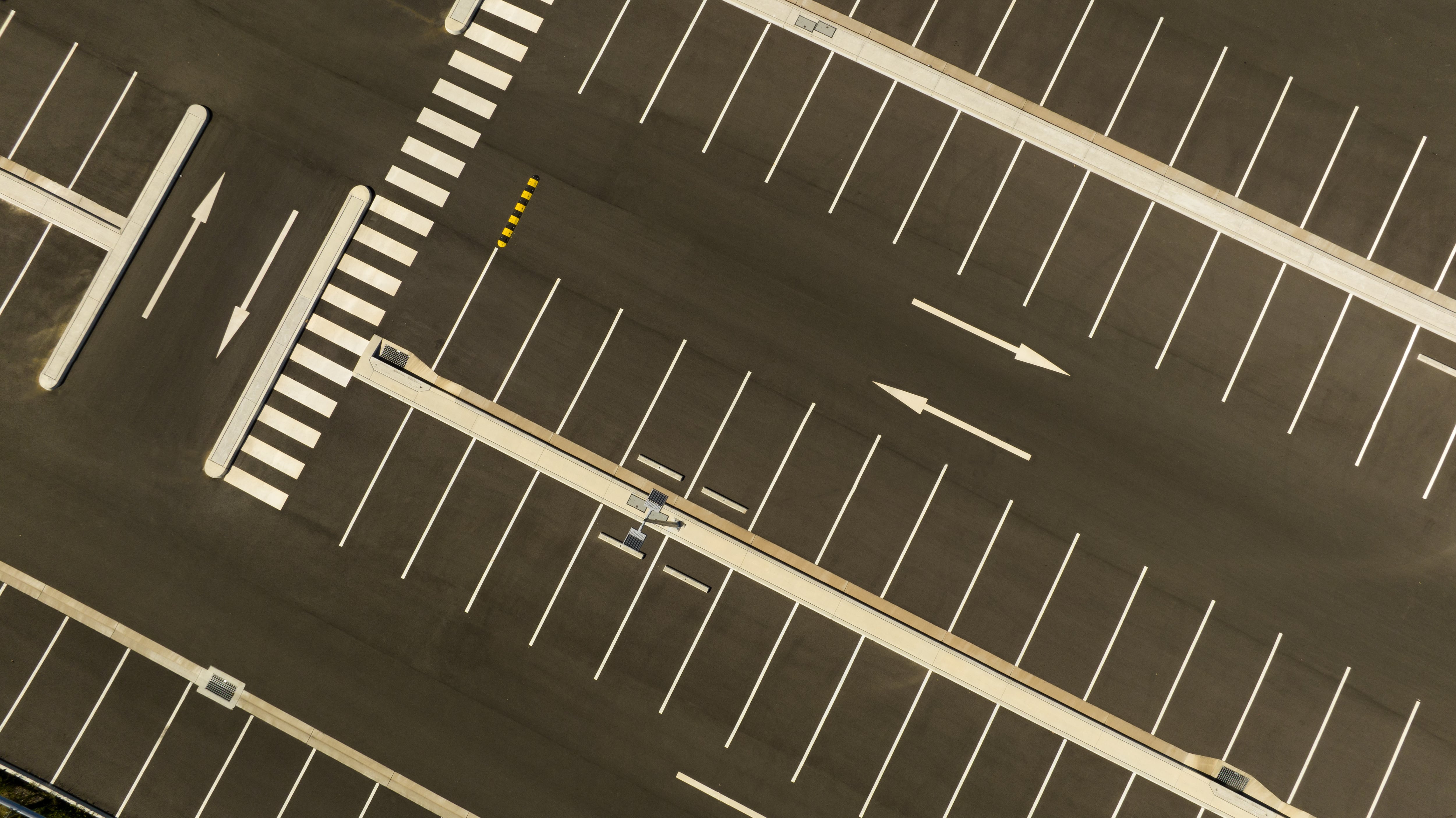 Diagonal car spaces with white lines and concrete blacks between rows parking.