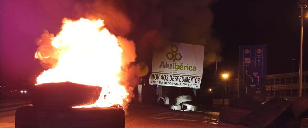 Un neumático ardiendo ante la sede de Alu Ibérica en la primera jornada de huelga