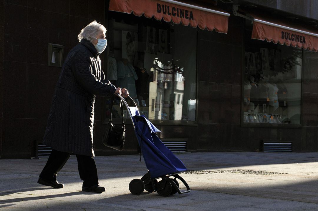 Una anciana camina por una calle con mascarilla, en una imagen de archivo