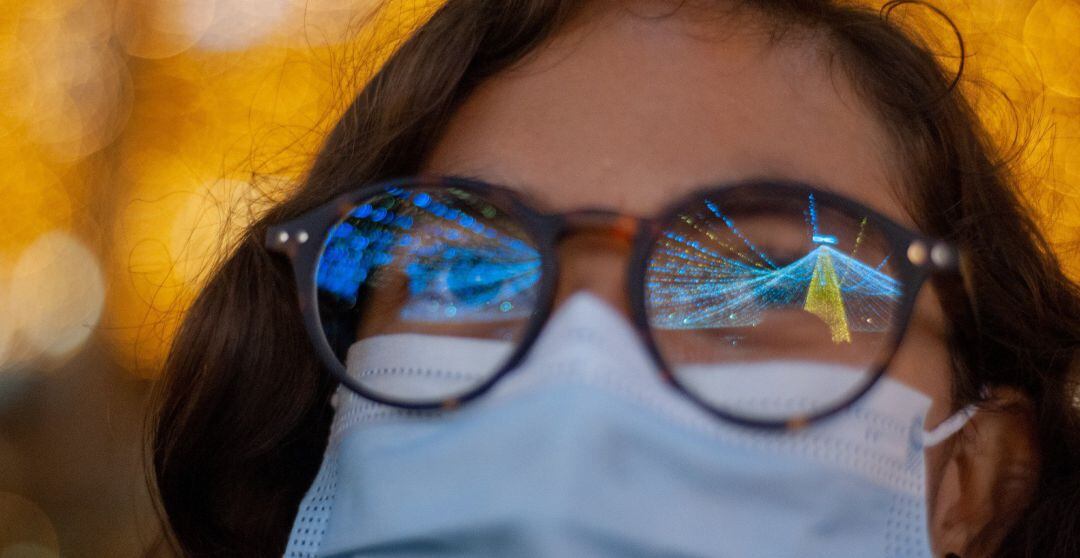 Una mujer viendo las luces de Navidad con mascarilla en plena pandemia del coronavirus.