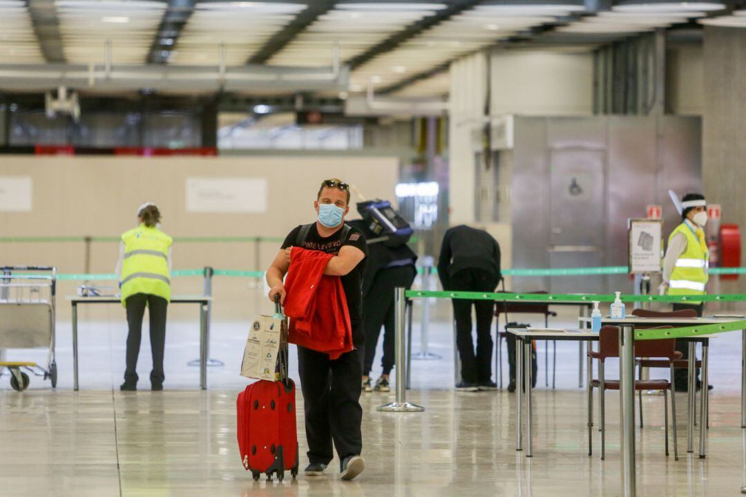 Un hombre camina tras pasar un control en el Aeropuerto de Madrid-Barajas Adolfo el día en el que se estrena el triple control sanitario de seguridad contra el Covid-19 que consiste en especificar si se ha pasado la enfermedad y en qué condiciones; seguido de un control de temperatura y otro visual, durante la apertura de las fronteras Schengen coincidiendo con el fin del estado de alarma que permite también el desplazamiento de viajeros nacionales a lo largo del territorio. 