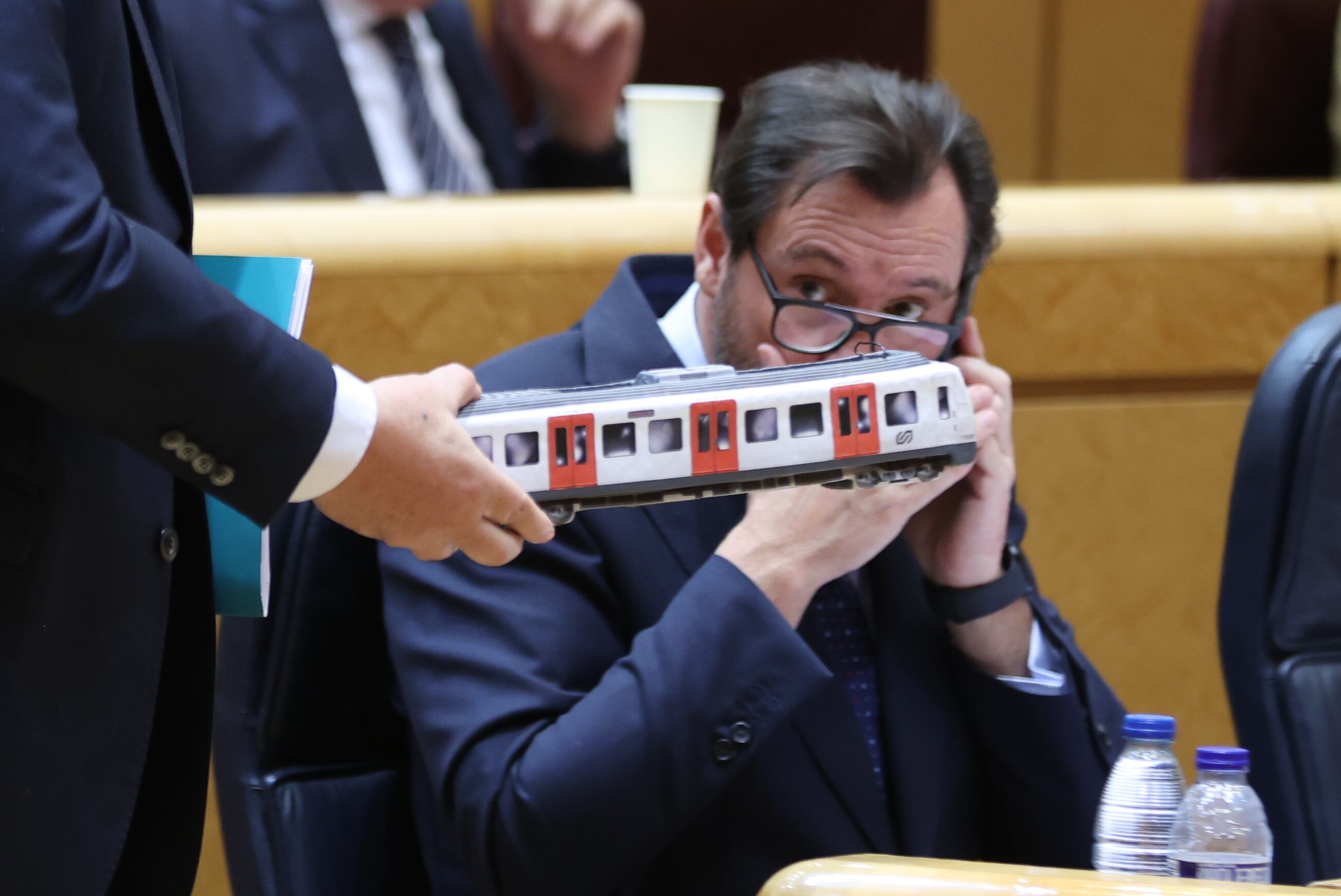 El ministro de Transportes, Óscar Puente, observa una maqueta de un vagón de tren que le muestra el senador de Junts Eduard Pujol durante la sesión en el Senado