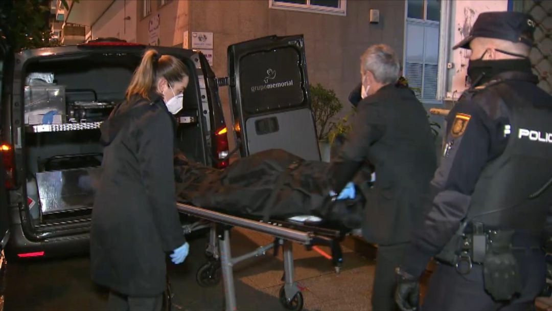 Trabajadores de la funeraria introduciendo el cadáver en el coche fúnebre