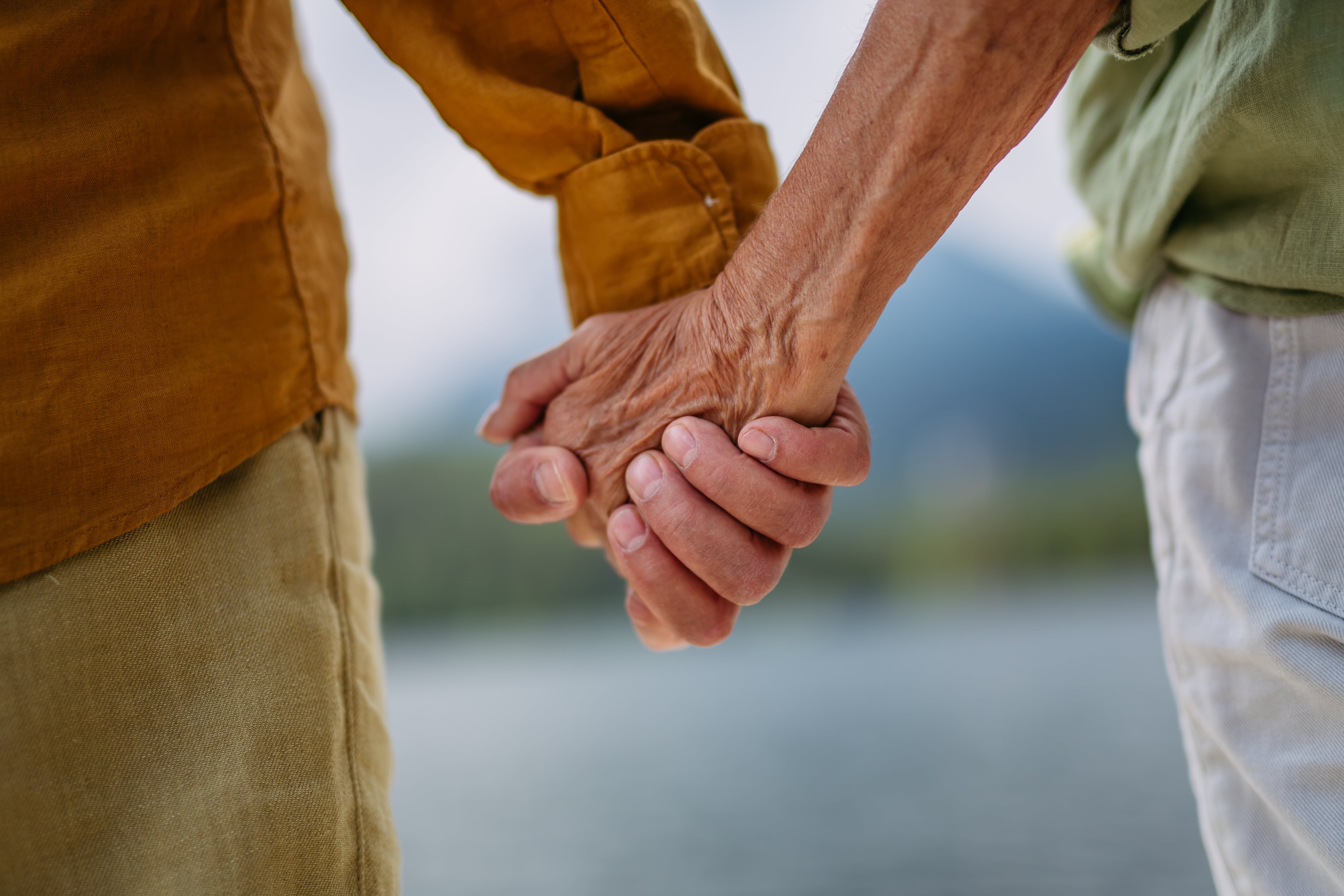 Una pareja de ancianos cogiéndose la mano.