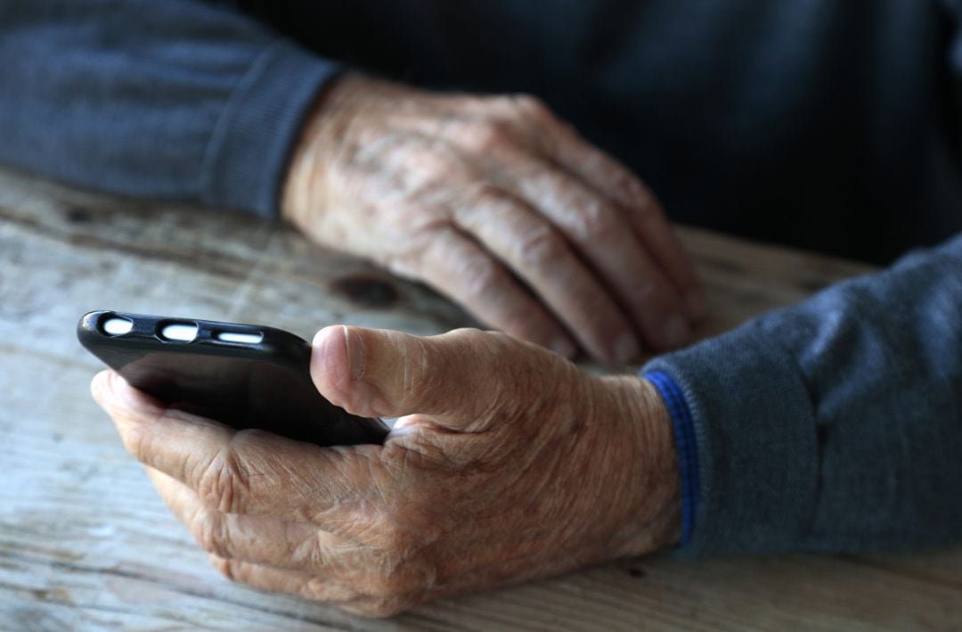 Un hombre sujeta un teléfono móvil.