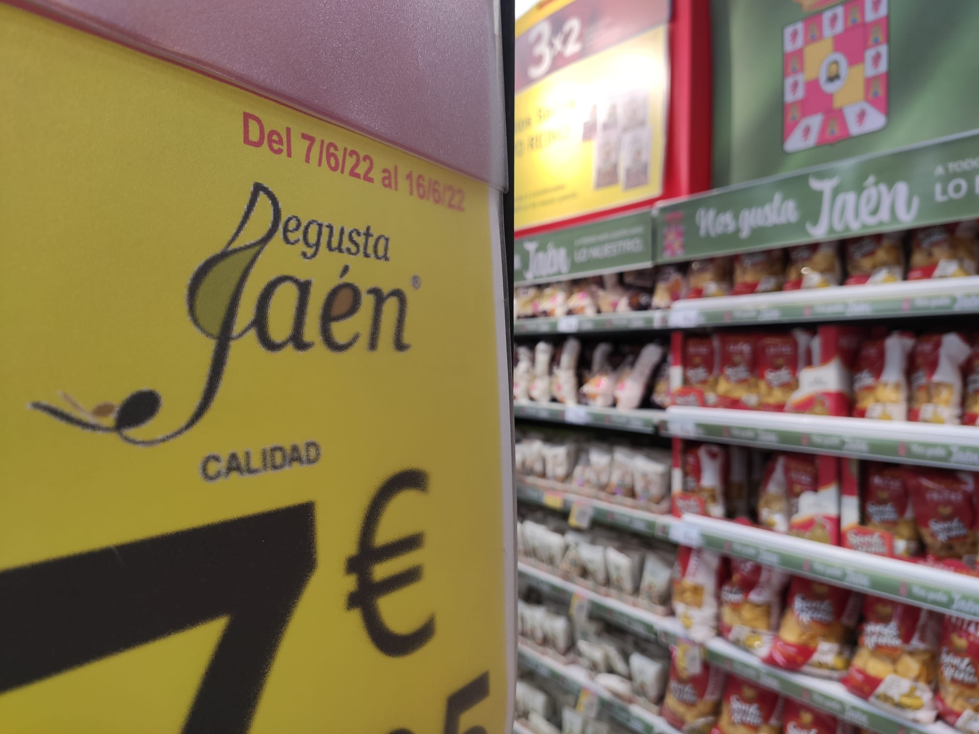 Cartel promocional en un supermercado jiennense, con productos alimentarios de fondo