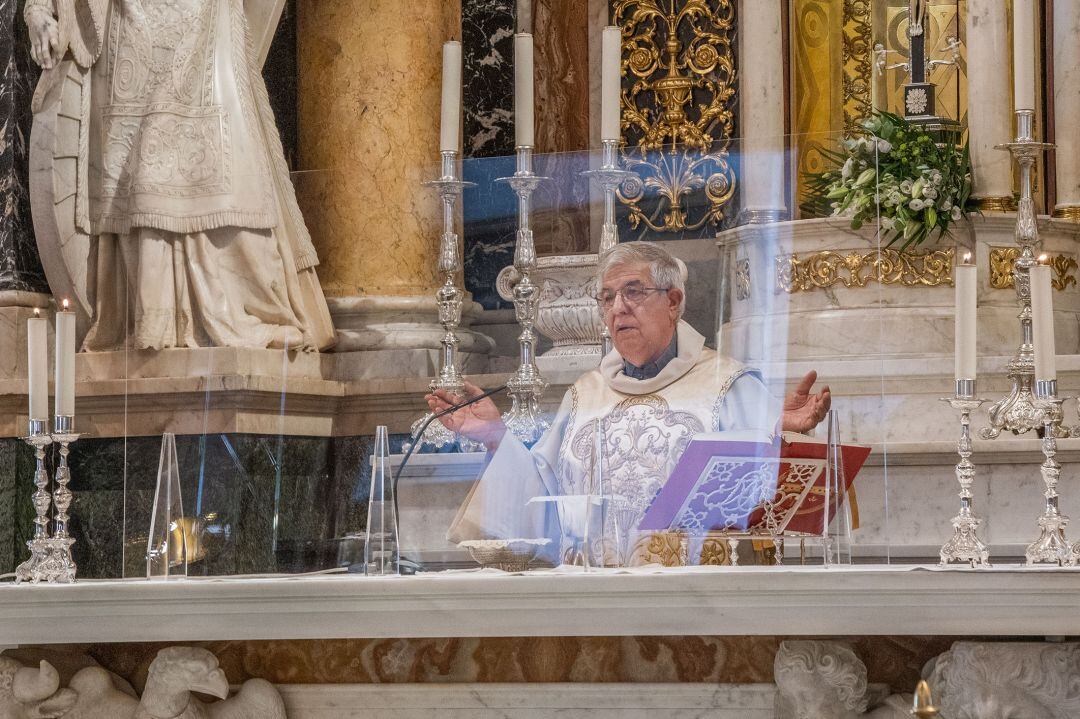 El rector de la Basílica de la Virgen de los Desamparados oficia misa tras una mampara de metacrilato para no llevar mascarilla