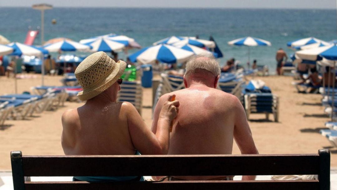 Dos turistas toman el sol en la playa de Benidorm, una de las más típicas dentro del programa del Imserso