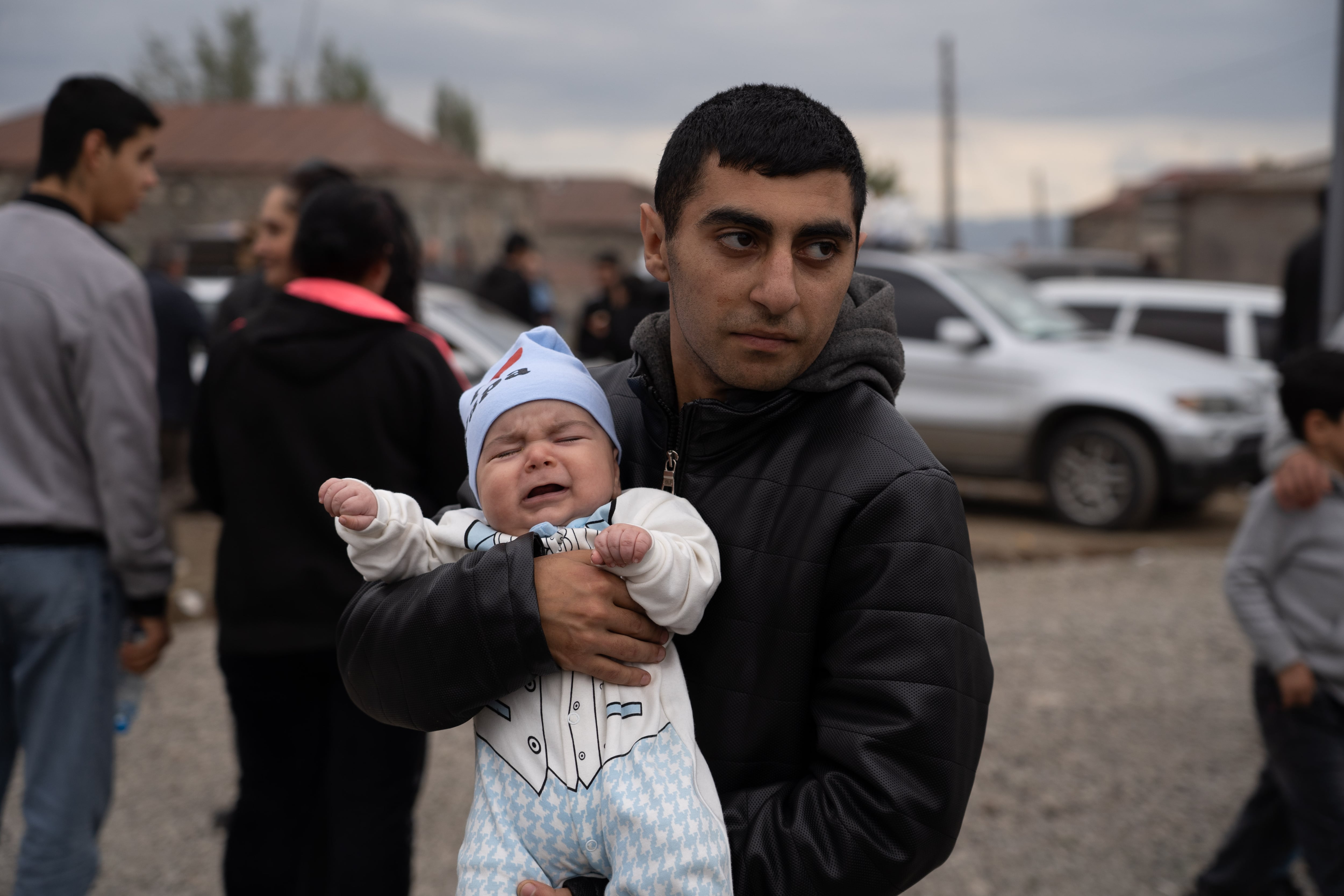 Un padre armenio sostiene a su bebé junto a las tiendas dispuestas por la Cruz Roja en la ciudad fronteriza de Jornidzor