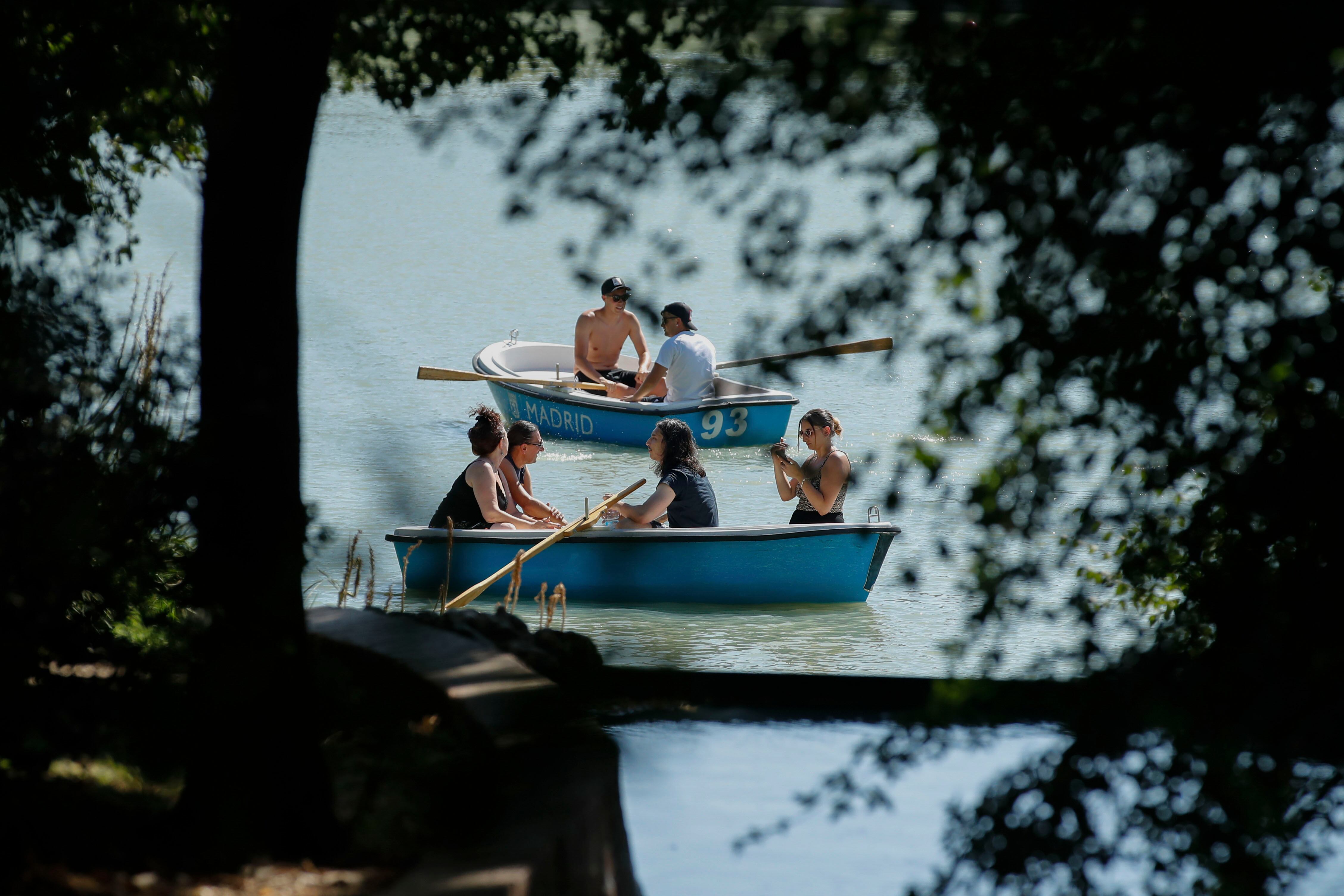 Varias personas reman en las embarcaciones del Parque del Retiro durante una jornada de intenso calor en la capital.