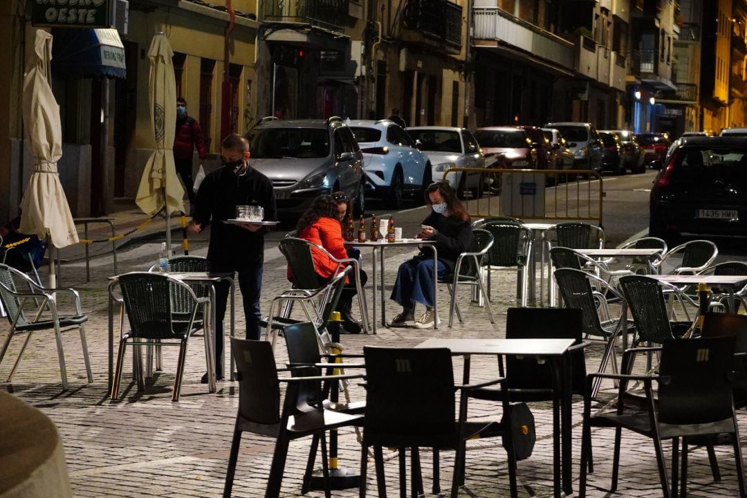 Un camarero trabaja en la terraza de un bar donde tres chicas consumen unas bebidas en Salamanca