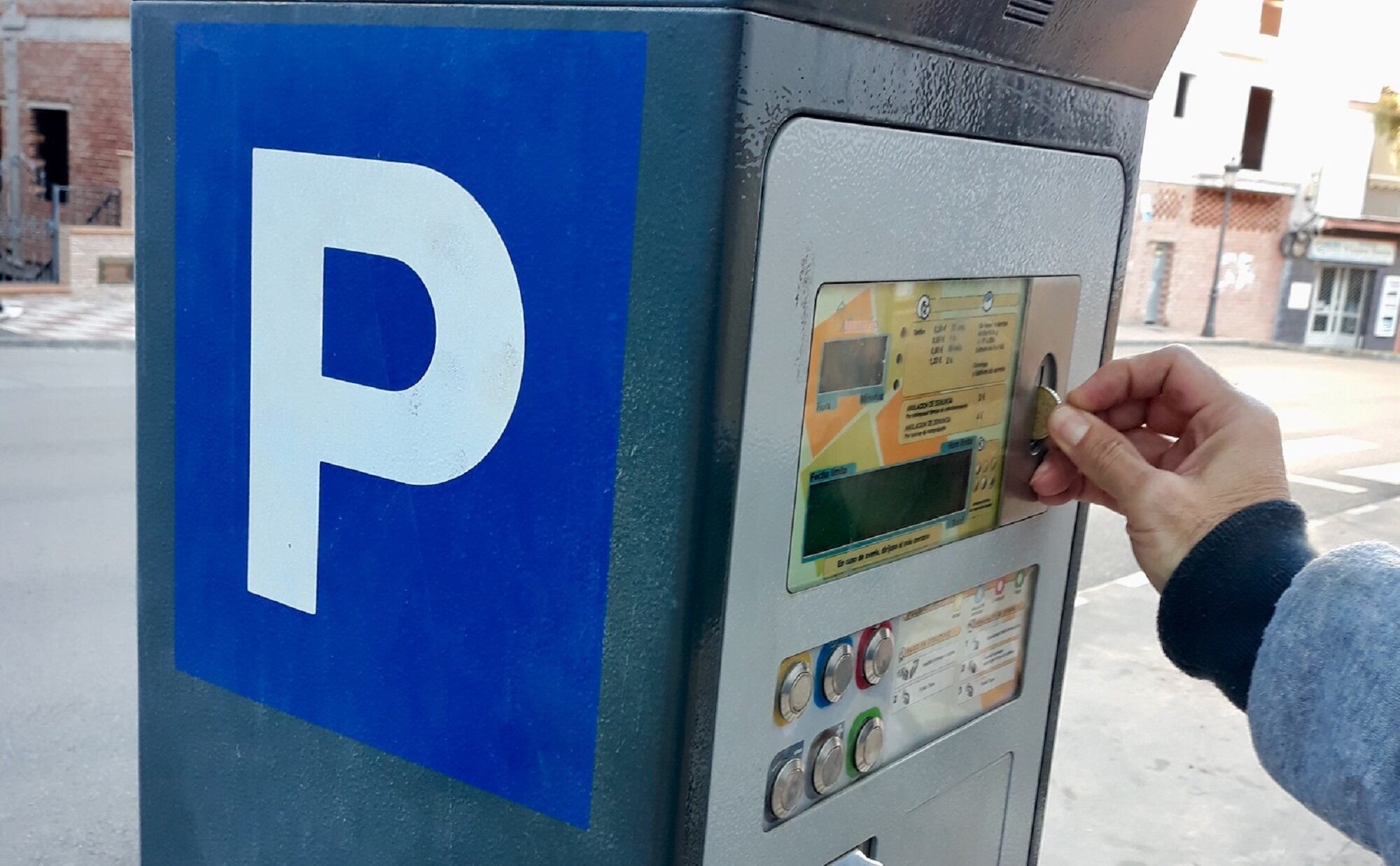 Un usuario introduce una moneda en un parquímetro