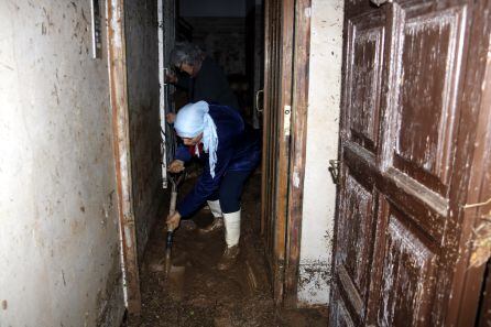 Imatge d'una dona retirant fang i aigua de l'entrada de casa a l'Albi, aquest dimecres