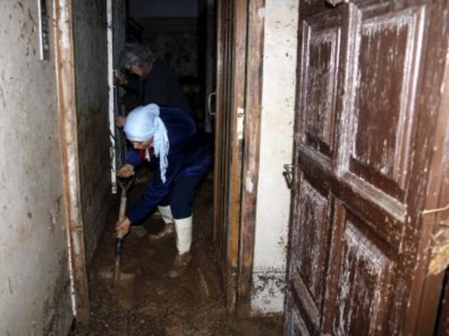 Imatge d'una dona retirant fang i aigua de l'entrada de casa a l'Albi, aquest dimecres