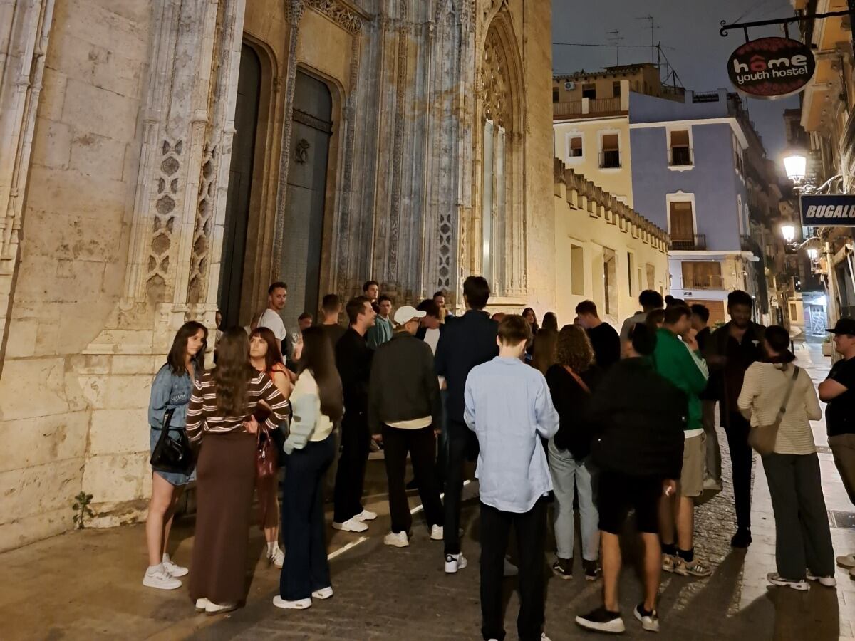 Un grupo de personas bebe y charla ante una de las puertas de la Lonja de la Seda