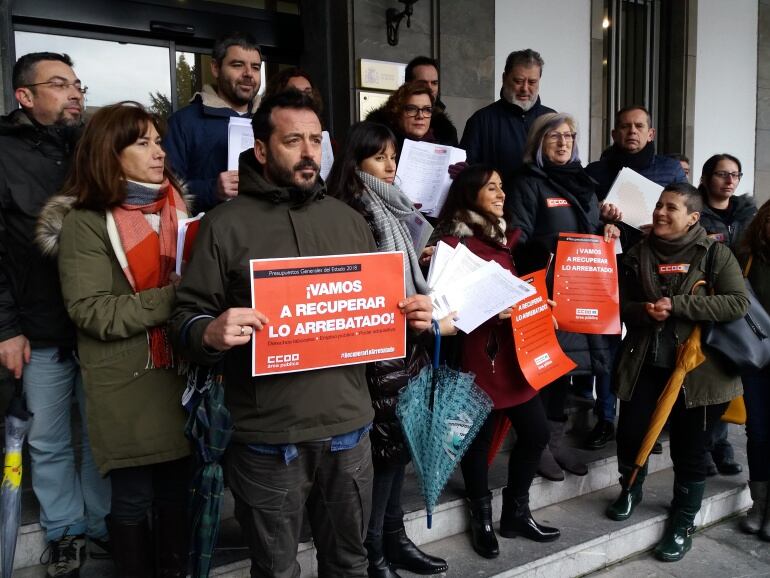 Representantes de CC.OO. posan con carteles alusivos a la campaña a las puertas de la Delegación del Gobierno