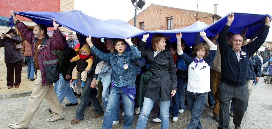 Los simpatizantes de Tierra Comunera se resguardan de la lluvia debajo de una bandera en el día de Castilla y León en Villalar de los Comuneros (Valladolid)