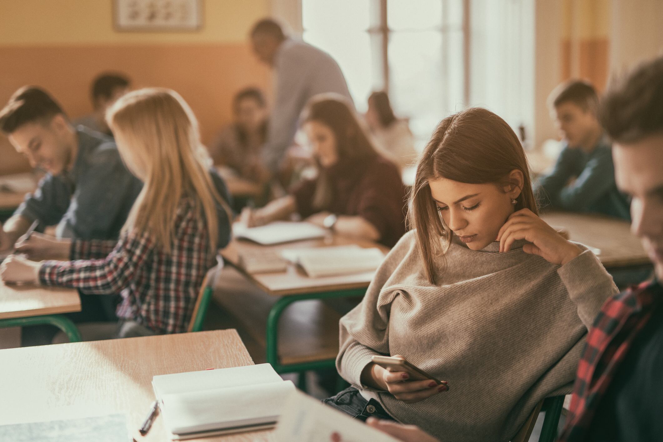 Una alumna contempla su teléfono móvil en un aula de un centro educativo