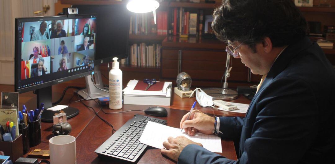 David Pérez, consejero de Administración Local, en su despacho durante un encuentro con alcaldes de ciudades afectadas por restricciones a la movilidad. En la pantalla aparecen los regidores de Parla, Fuenlabrada o Getafe.