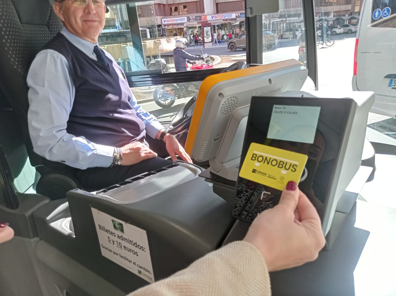 Una pasajera pasa su bono en el autobús urbano