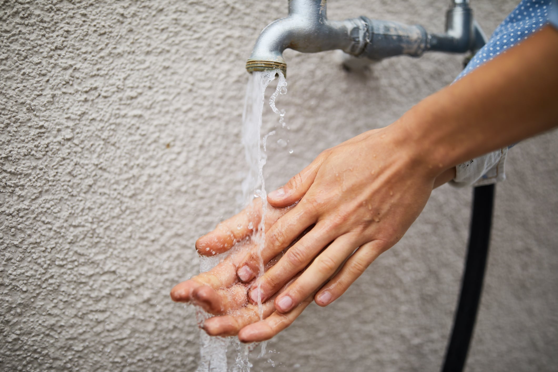 Una mujer se lava las manos en un grifo del que sale agua.