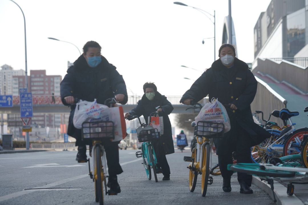 Varios ciudadanos circulan en bicicleta por las calles de Pekín