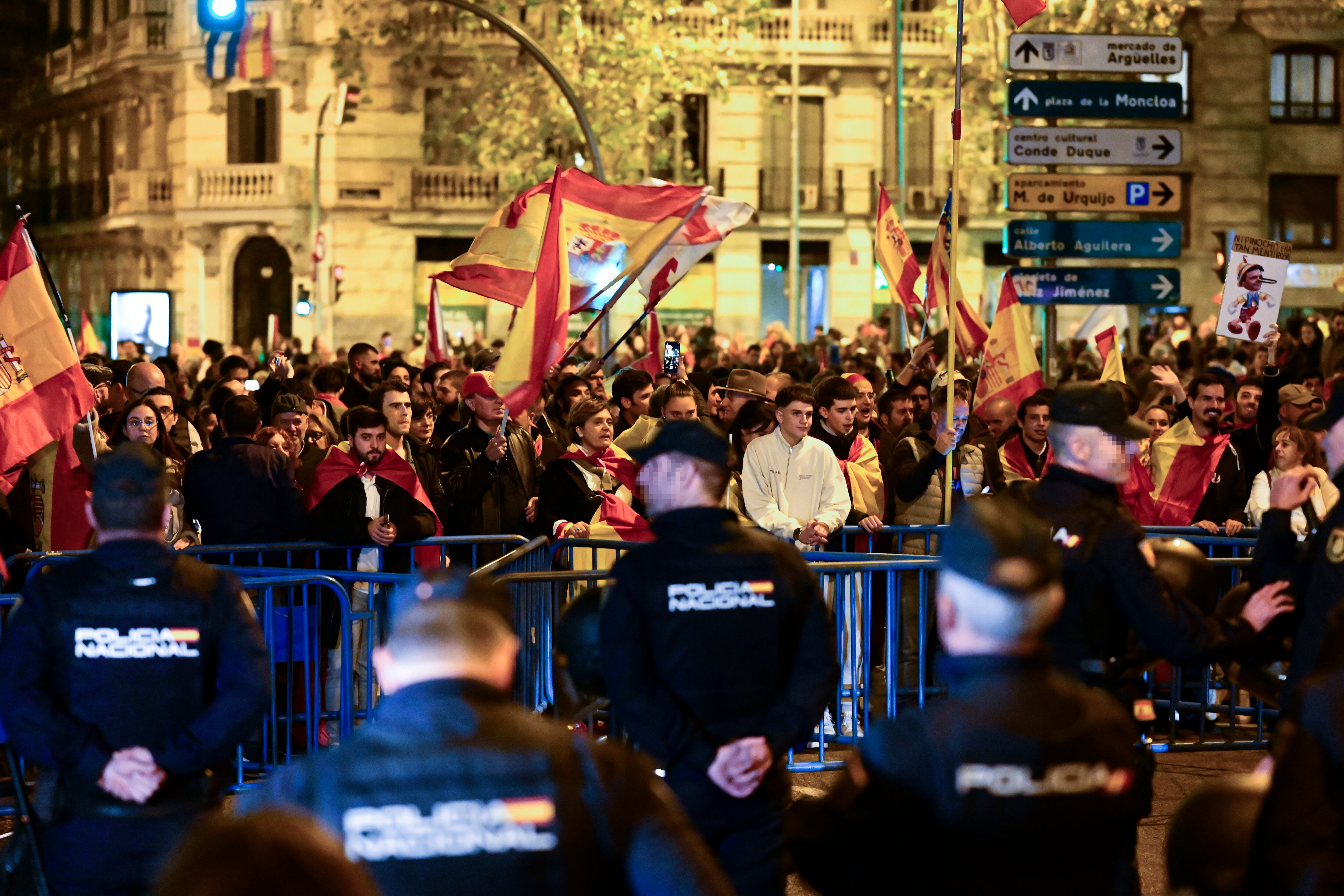 Unos jóvenes sostienen banderas y pancartas frente a efectivos de la Policía durante la manifestación que han trasladado hasta las inmediaciones de La Moncloa y los accesos de la A-6 a la capital, este sábado.