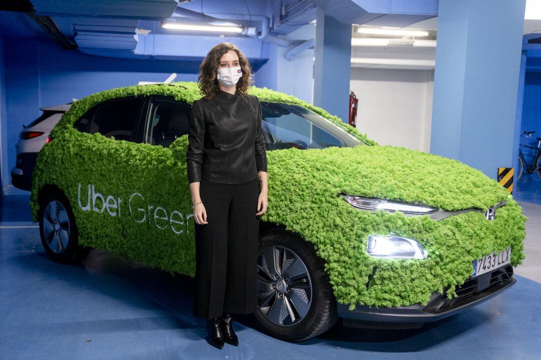 La presidenta de la Comunidad de Madrid, Isabel Díaz Ayuso, posan con un vehículo que promociona Uber Green, en la presentación de Uber Green, en la sede de Uber