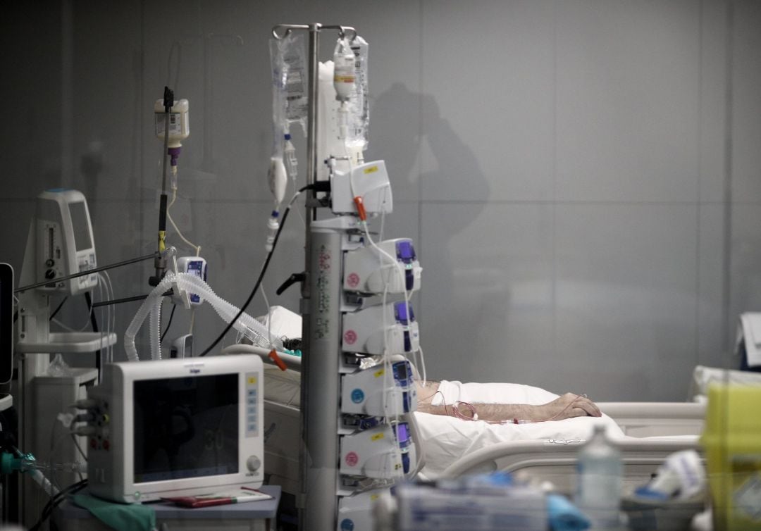 Mano de un enfermo con vía subcutánea en una cama de la UCI del Hospital de Emergencias Isabel Zendal.