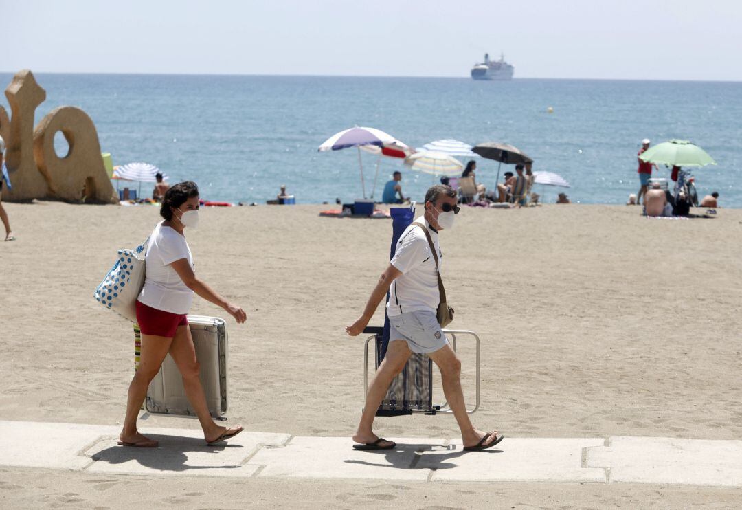 Dos personas con mascarilla acceden a la playa