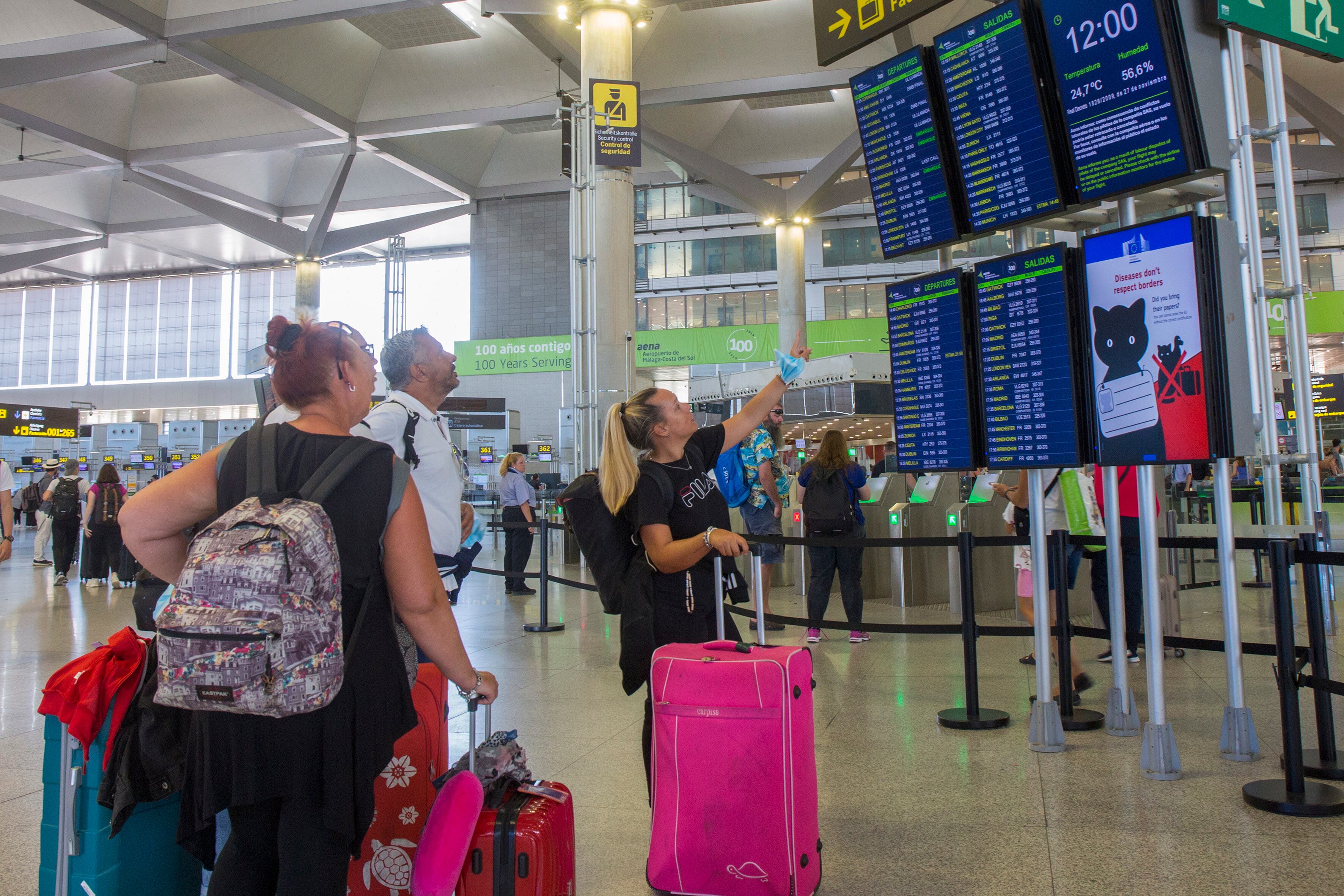 GRAFAND1510. MÁLAGA, 13/07/2022.- Varias personas miran los paneles informativos de los vuelos en la Terminal 3 de salidas del aeropuerto de Málaga, durante la segunda jornada de huelga de esta semana de los tripulantes de cabina de pasajeros convocada en Ryanair por los sindicatos USO y Sictpla que ha ocasionado este miércoles retrasos en 22 vuelos con origen o destino en los aeropuertos de Málaga y Sevilla, pero no ha supuesto la cancelación de ninguna operación. EFE/Álvaro Cabrera