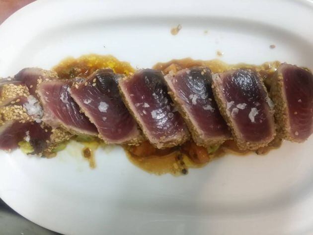 Tataki de bonito sobre cama de tomate y aguacate con curry y soja