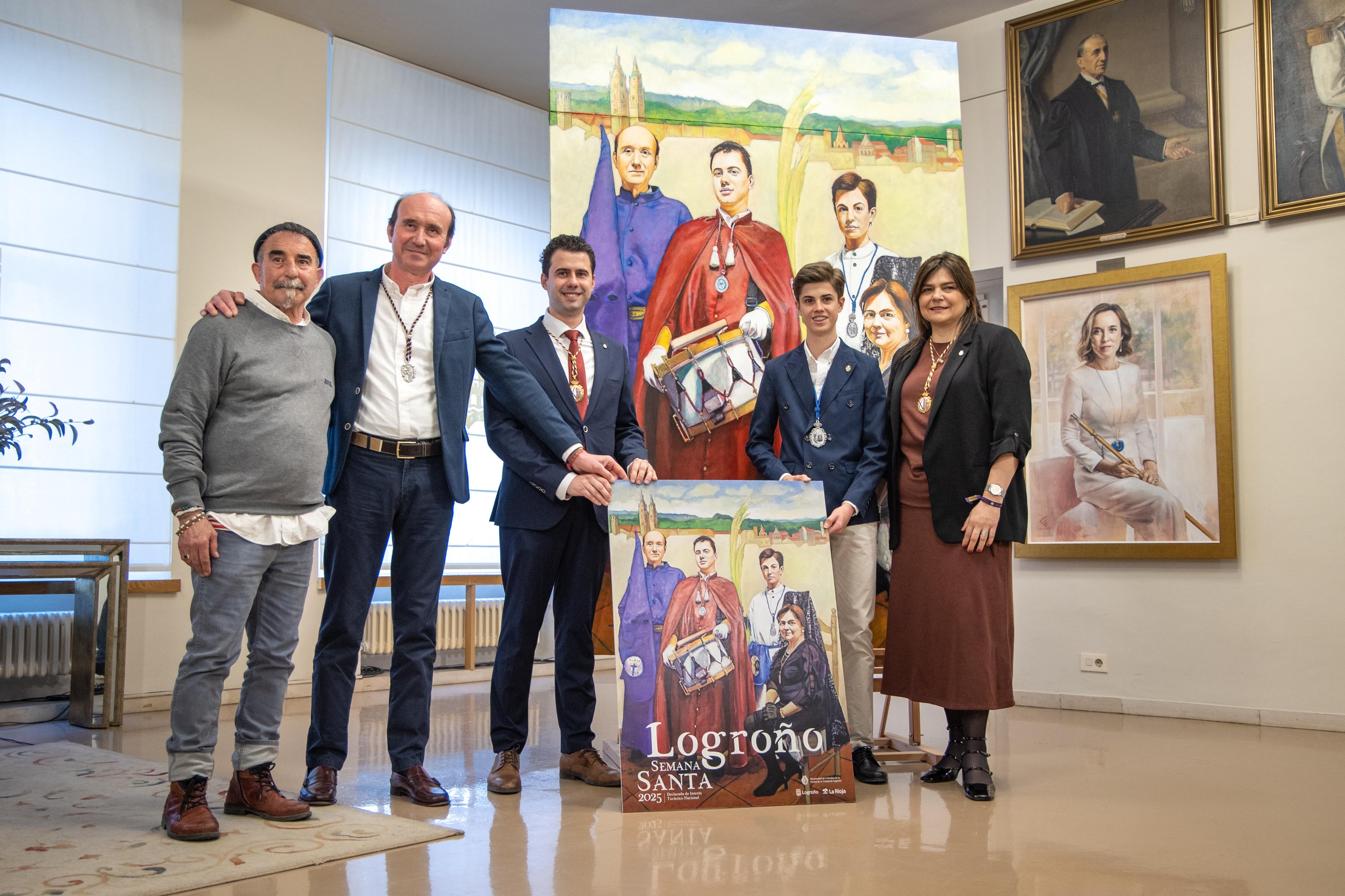 LOGROÑO, 05/03/2025.- El pintor Luis Burgos (i), posa junto a la obra y a los personajes pintados. Burgos ha retratado a una familia de cofrades, formada por los padres y sus dos hijos ataviados con los trajes de diferentes cofradías logroñesas, en un cuadro para ilustrar el cartel de la Semana Santa de Logroño 2025. Luis Ignacio Arruti (3i), de la Cofradía de la Flagelación de Jesús, y Elena Álvarez (d), de la Hermandad de Cofradías, posan en el lienzo como &quot;padres&quot; de Antonio García (2i), de la Cofradía Jesús Nazareno y Nuestra Señora de los Dolores, y Rafael Vivanco (2d), de la Cofradía de la Entrada de Jesús en Jerusalén.-EFE/Raquel Manzanares
