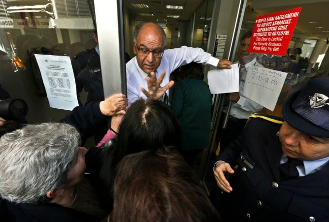 Un gerente del Laiki Bank intenta calmar a los ciudadanos que esperan a las puertas de una sucursal en Nicosia