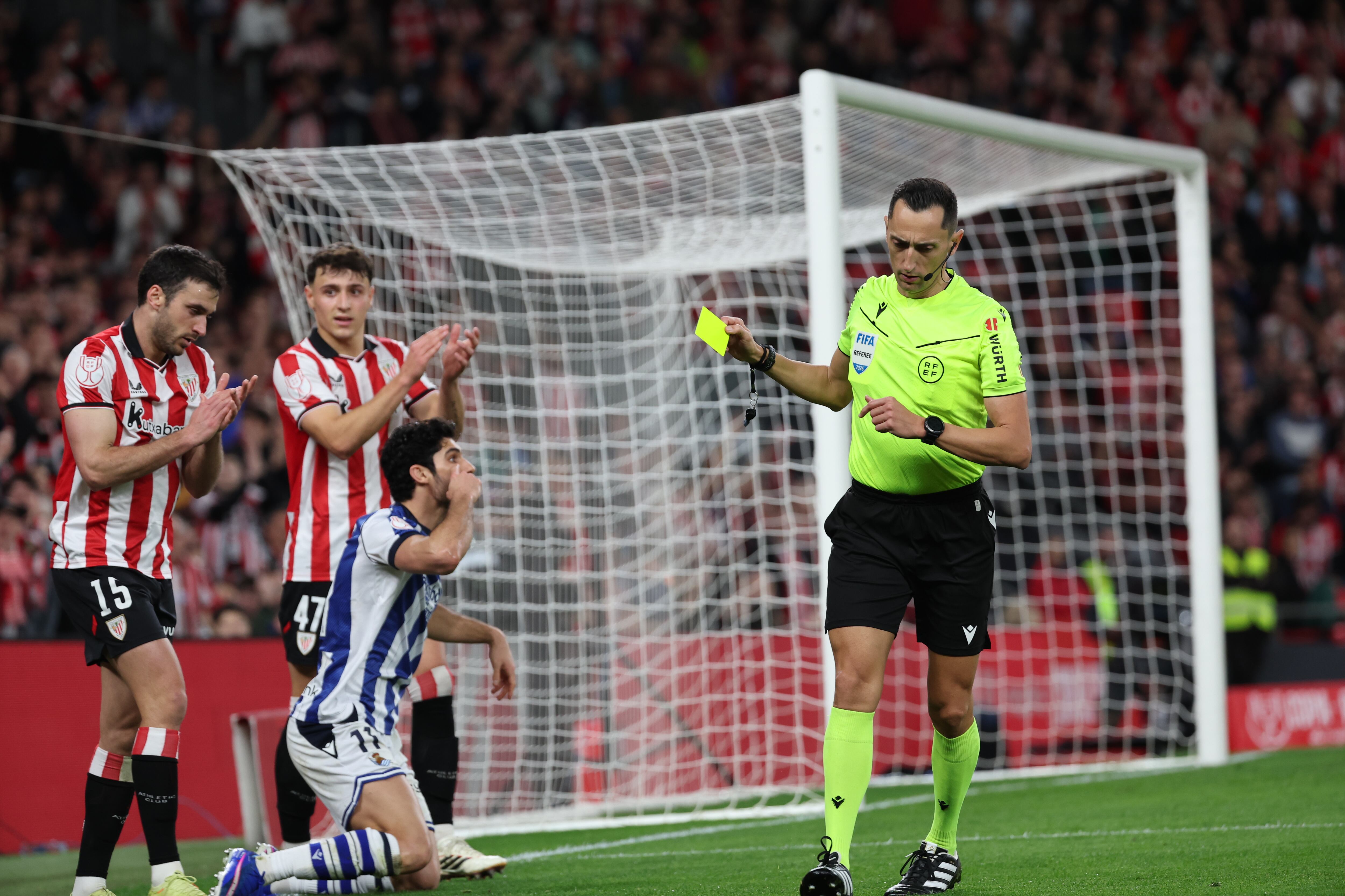 BILBAO, 11/02/2026.- El colegiado Sánchez Martínez saca tarjeta amarilla al centrocampista de la Real Sociedad Gonçalo Guedes (3i), durante el partido de ida de la semifinales de la Copa del Rey que Athletic Club de Bilbao y Real Sociedad disputan este miércoles en el estadio de San Mamés, en Bilbao. EFE/Luis Tejido