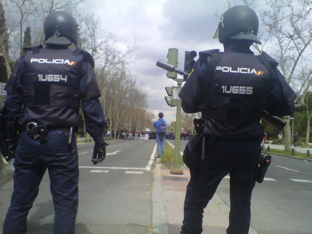 Dos efectivos de la Policía Nacional frente a decenas de manifestantes