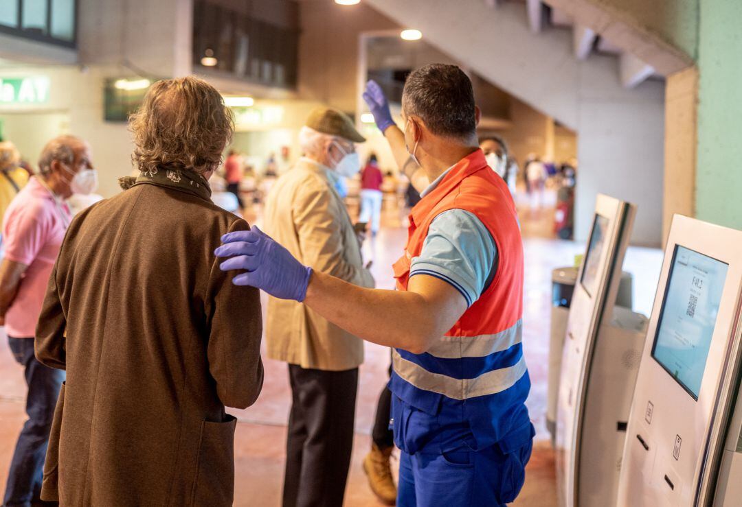 Una hombre  de Protección Civil, dirige a las personas que van a recibir la vacunar contra el Covid-19, a 28 de abril de 2021, en el Estadio de la Cartuja, en Sevilla.