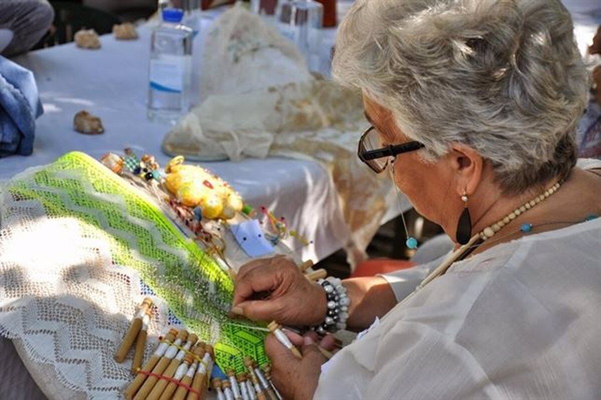 Una señora realiza encaje de bolillos