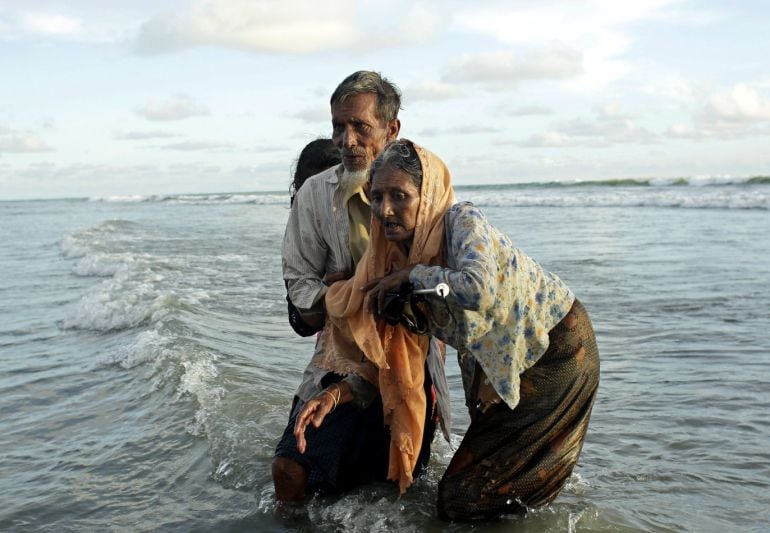 Tres refugiados de la etnia rohinyá, caminan hacia la orilla tras cruzar el río Naf, que marca la frontera de Bangladesh y Birmania