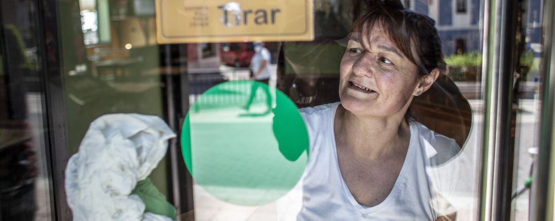 Mujer limpiando la puerta de su negocio