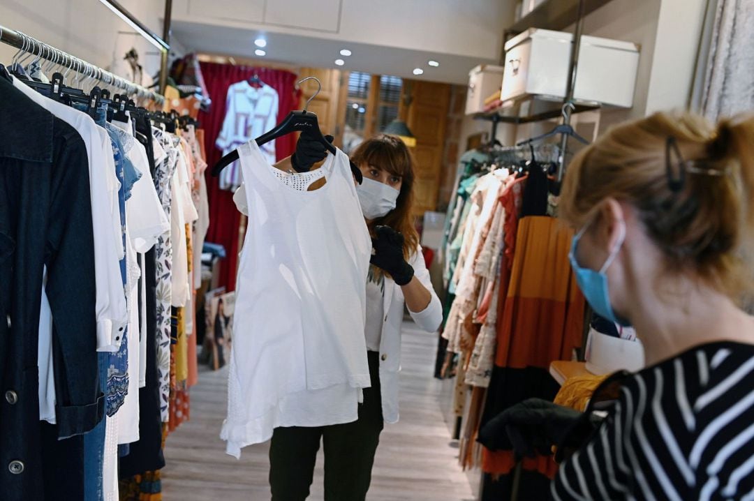  Una trabajadora muestra ropa a una clienta en un comercio de Alcalá de Henares, tienda dotada de desinfección constante mediante ozono.