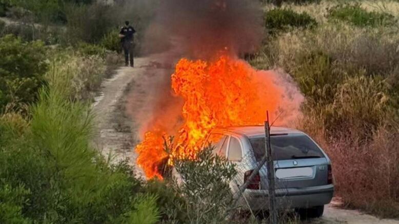 Actuación conjunta de los bomberos y la policía local durante la intervención para controlar el incendio del vehículo tras el accidente en Albaida